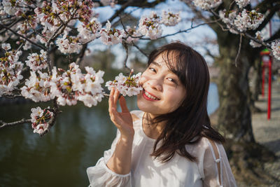 Portrait of smiling young woman with cherry blossom