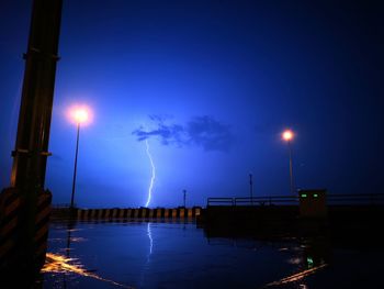 Illuminated street lights against sky at night