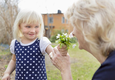 Girl giving grandmother flowers to smell