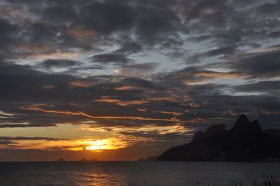 Scenic view of sea against dramatic sky during sunset