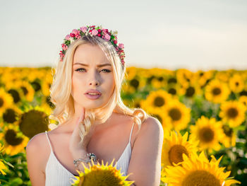Portrait of woman wearing wreath against sunflower field