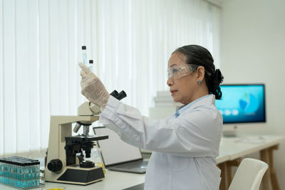 Side view of doctor examining chemical in laboratory