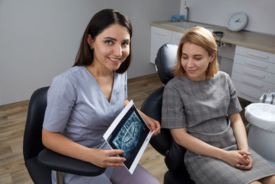 Portrait of smiling friends using laptop at home