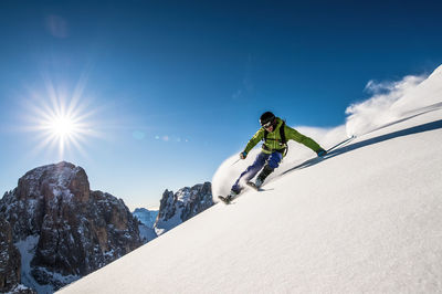 Low angle view of person skiing on snowcapped mountain against sky