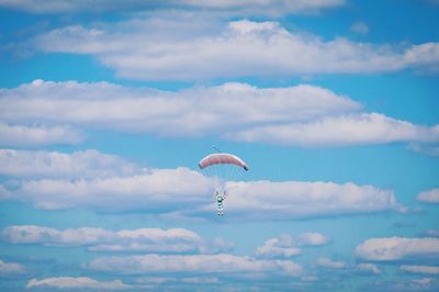 Low angle view of person paragliding in cloudy sky