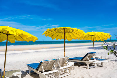 Lounge chairs and parasols on beach against sky