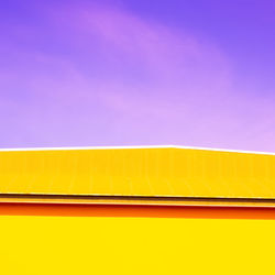Close-up of yellow wall against blue sky