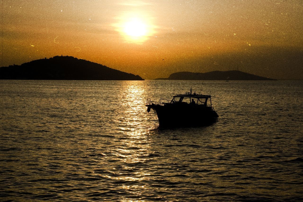 SILHOUETTE BOAT IN SEA AT SUNSET