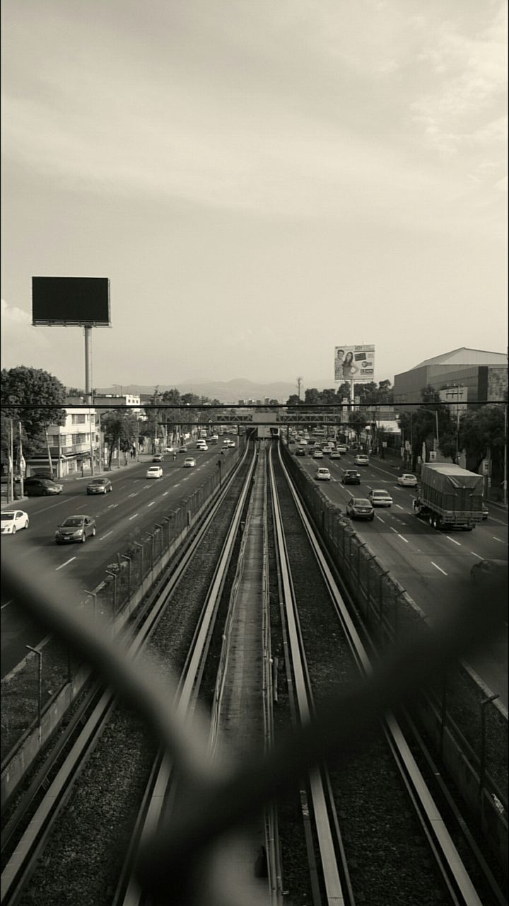 transportation, railroad track, built structure, architecture, rail transportation, sky, building exterior, the way forward, public transportation, city, diminishing perspective, railroad station platform, high angle view, vanishing point, mode of transport, railroad station, train - vehicle, cloud - sky, road, no people