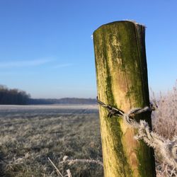 Close-up of wooden post on field against sky