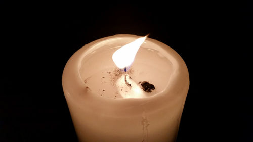 Close-up of illuminated candle against black background