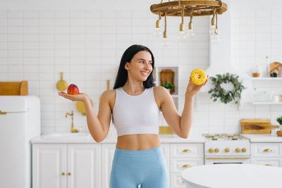 Young woman makes a choice between a peach fruit and a donut. the concept of diet and healthy eating