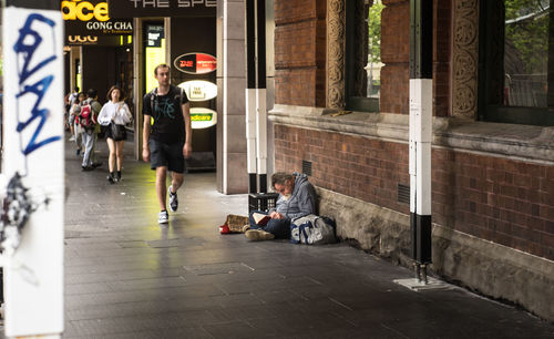 People sitting on footpath in city