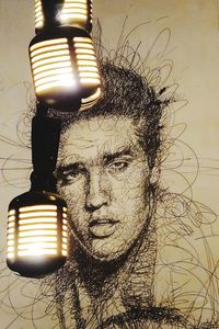 Close-up portrait of young man against illuminated lamp