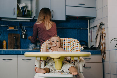 Rear view of mother and daughter sitting on floor