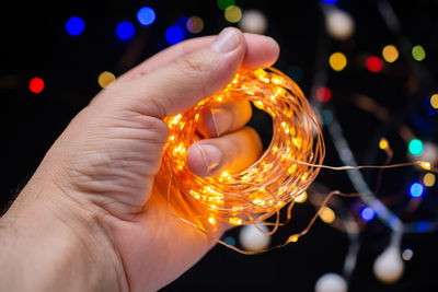 Close-up of hand holding illuminated string lights