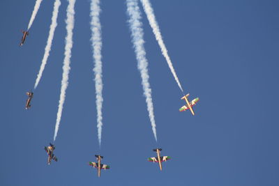 Low angle view of airshow against clear blue sky