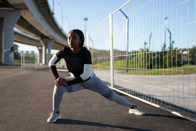 African american runner lunging near fence