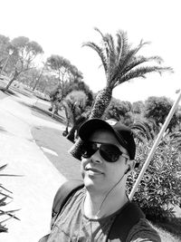 Portrait of young man wearing sunglasses against trees