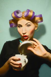 Portrait of woman holding ice cream cone against gray background