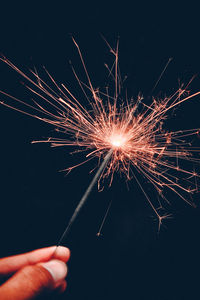 Close-up of hand holding illuminated sparkler at night