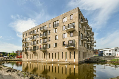 Buildings by river against sky