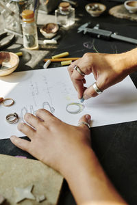 Hands of jeweller sketching ring design on paper at workbench