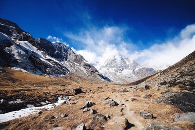 Scenic view of snow covered mountains against blue sky