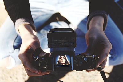 Low section of woman holding camera at beach