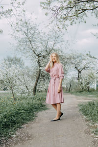 Blonde girl on a spring walk in the garden with cherry blossoms. female portrait. 