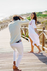 Full length of man photographing girlfriend while standing on footbridge