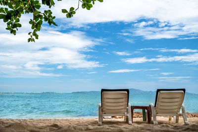 Chair on beach against sky