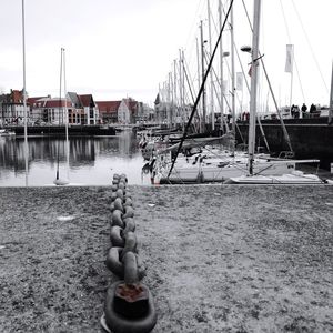 Sailboats moored at harbor against clear sky