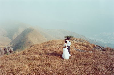 Woman with arms outstretched on mountain against sky
