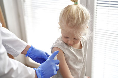 Doctor sanitizing girl arm at hospital