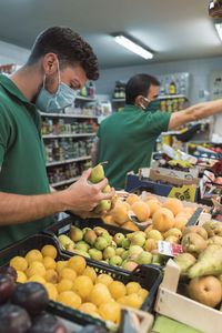 Two men selling fruit picking fruit from the stall