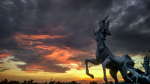 Low angle view of statue against storm clouds