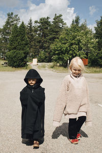 Brother and sister walking in park during sunny day