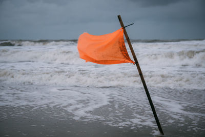 Red flag on sea against sky