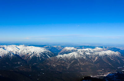 Scenic view of snowcapped mountains against blue sky