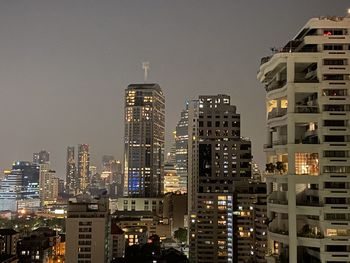 Illuminated buildings in city against sky at night