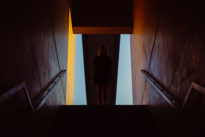 Rear view of woman standing on staircase against building