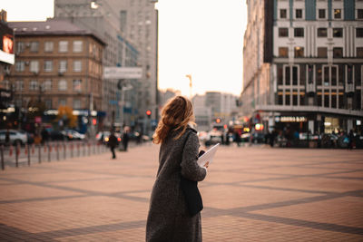 Side view of woman standing on street in city