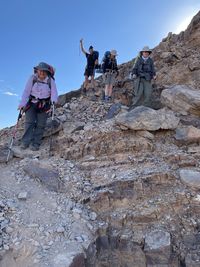 Low angle view of people on rock against sky