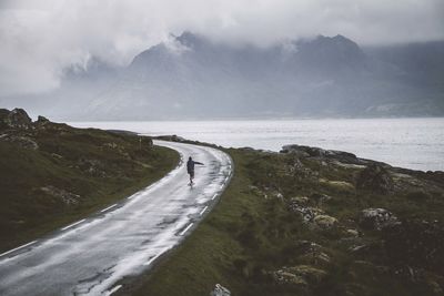 Rear view of man skateboarding on road