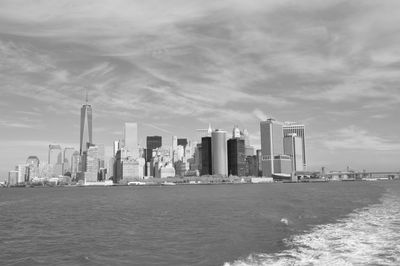 Sea by modern buildings against sky