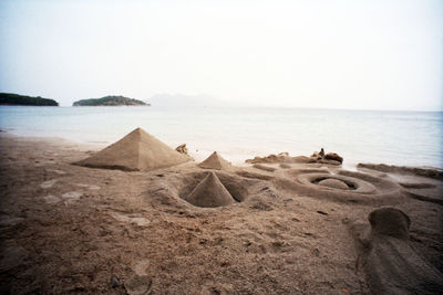 Pyramids made from sand at beach against clear sky