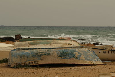 Abandoned car on beach against sky