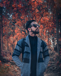 Portrait of young man standing in forest during autumn