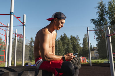 Man wearing cap using smart phone at park on sunny day